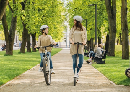 Petite fille sur un vélo accompagné d'une femme en trottinette éléctrique
