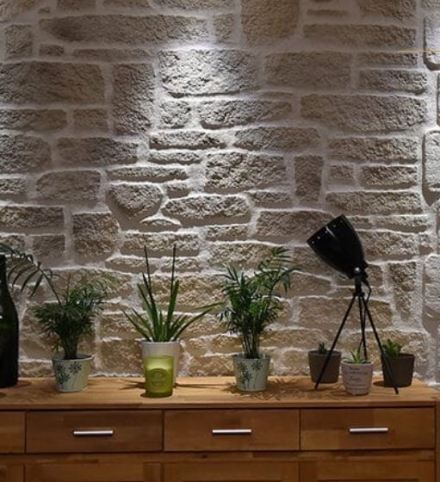 Plantes posées sur une commode avec un mur en pierre en fond